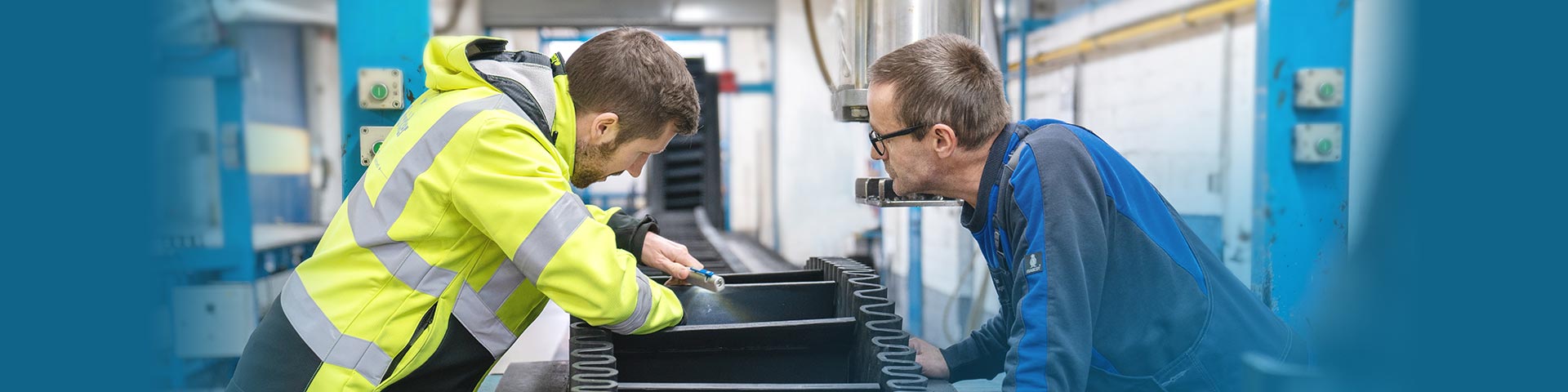 Blick auf zwei Mitarbeiter in der Produktion, welche ein Steilförderband fertigen.