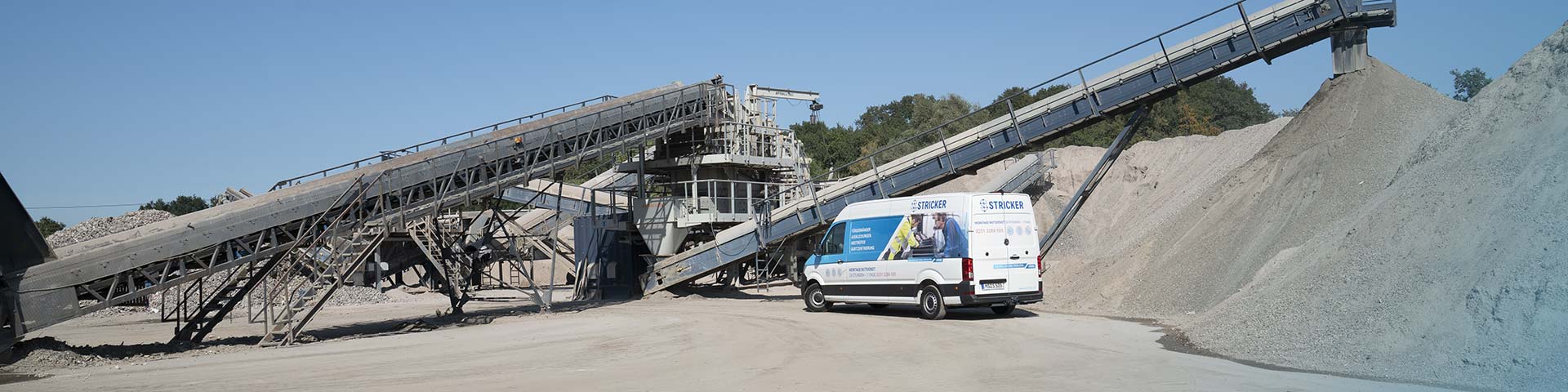 Blick auf eine Förderanlage mit einem STRICKER-Montagewagen davor.